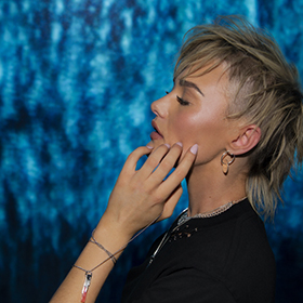 A girl stands against a blue background
